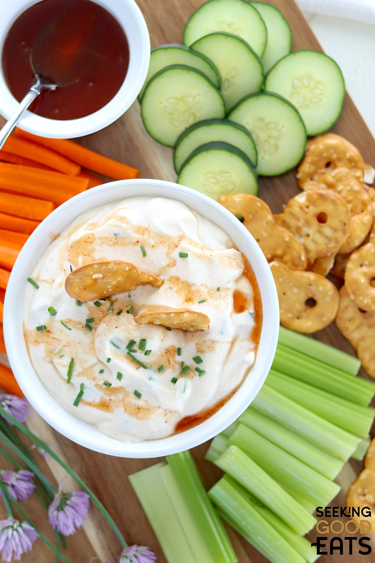 A white bowl with hot honey whipped cottage cheese dip with crackers and celery.
