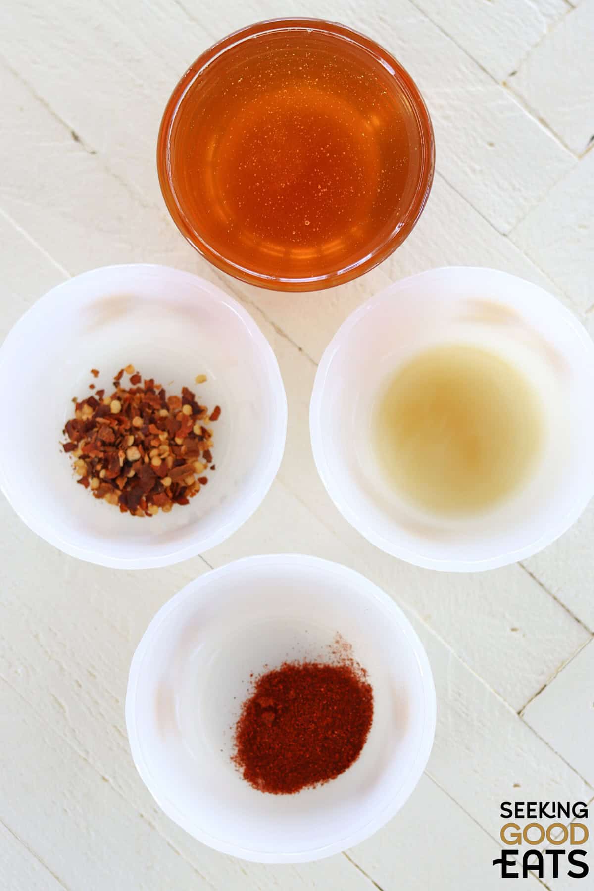 Ingredients needed for making homemade hot honey on a white wooded board.
