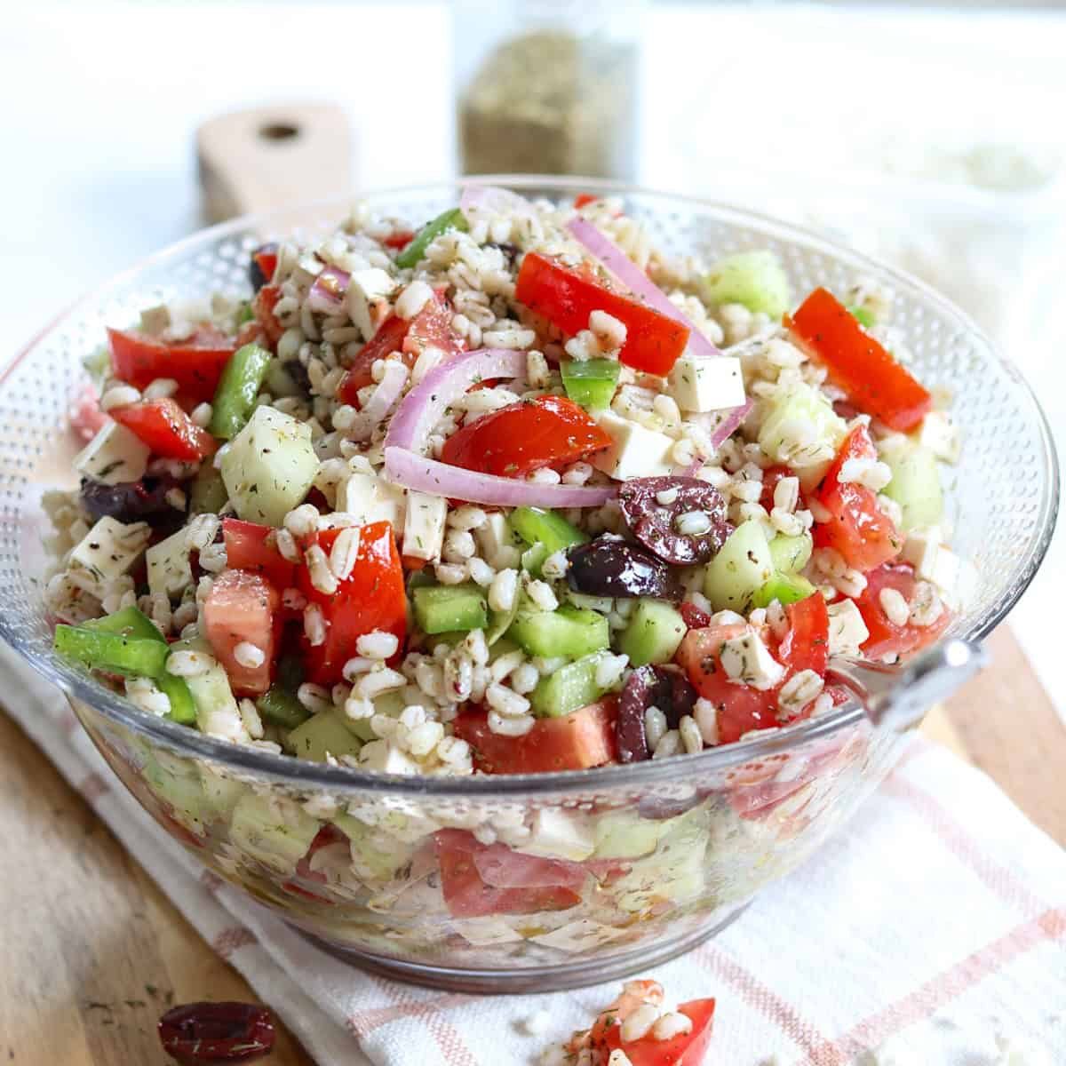 Mediterranean barley salad served in a bowl with a spoon.