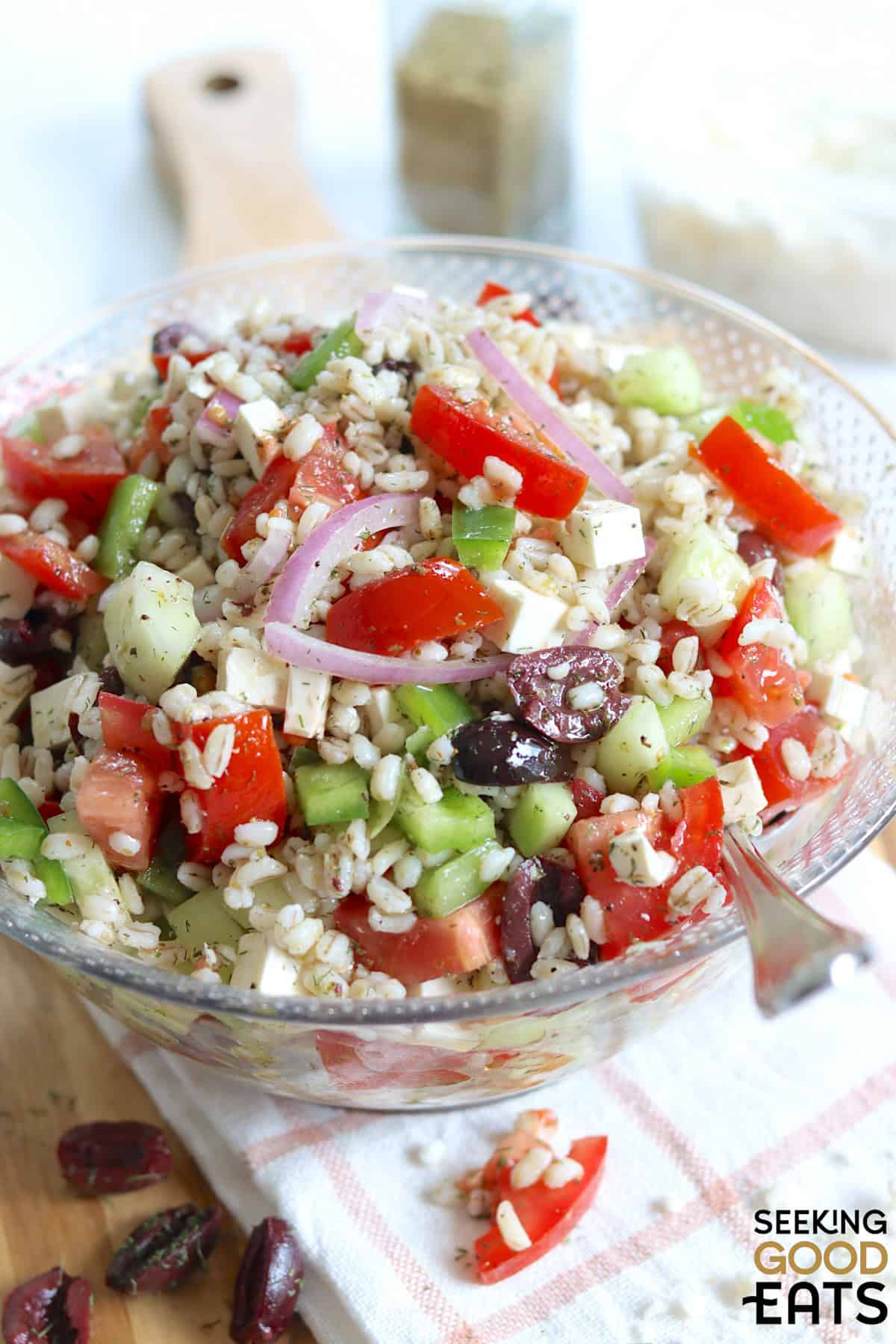 A clear glass salad bowl with Mediterranean barley salad.
