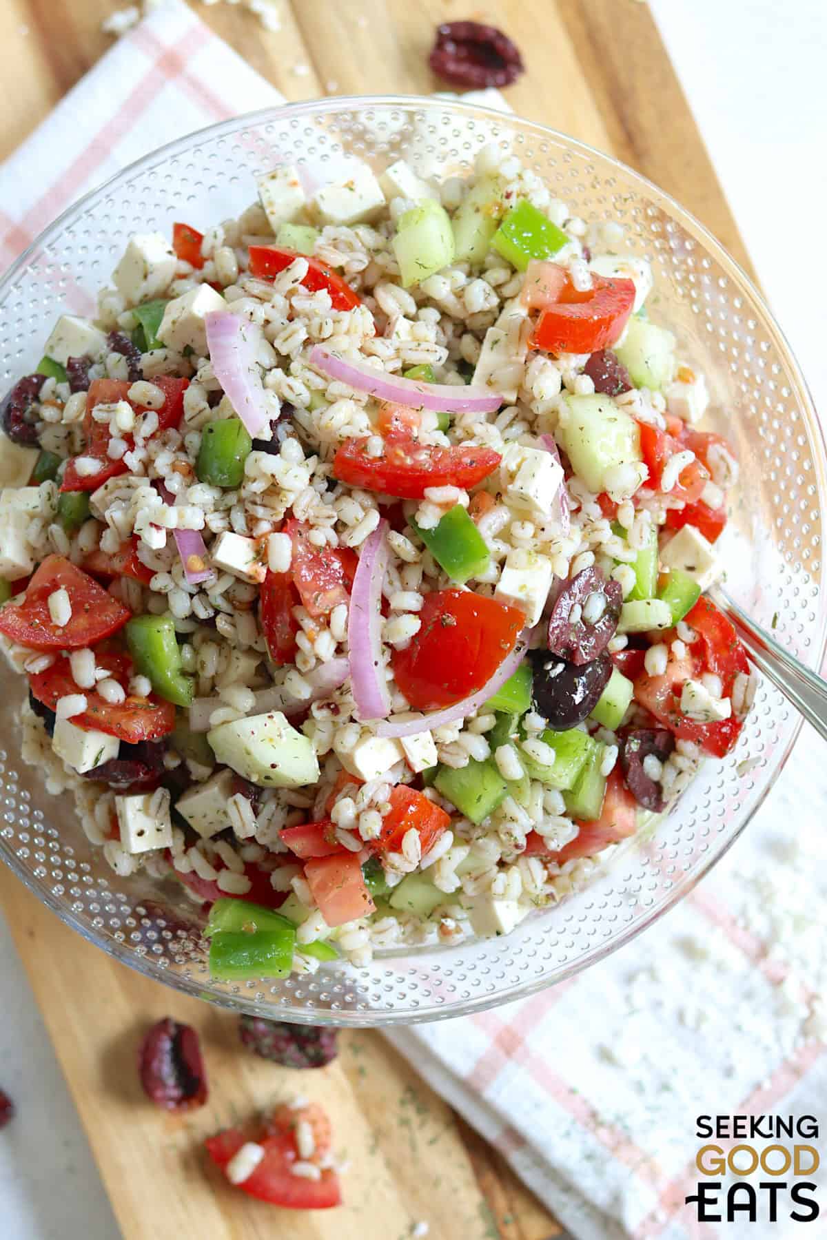 Mediterranean barley salad in a clear glass bowl.
