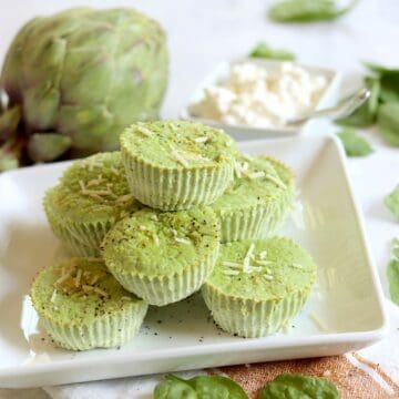 A square white plate of artichoke spinach egg bites topped with parmesan.