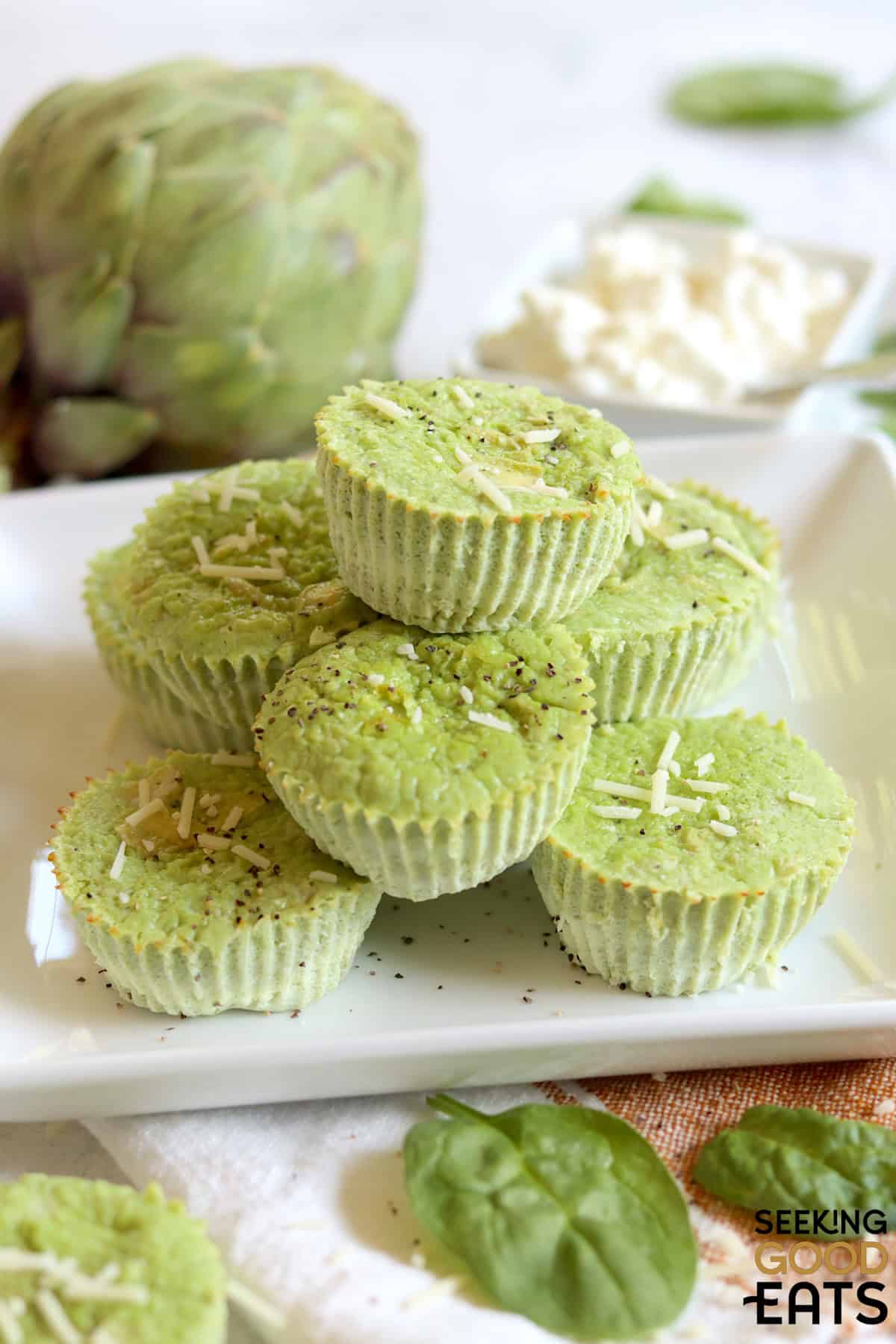 Artichoke spinach egg bites stacked on a square white plate.