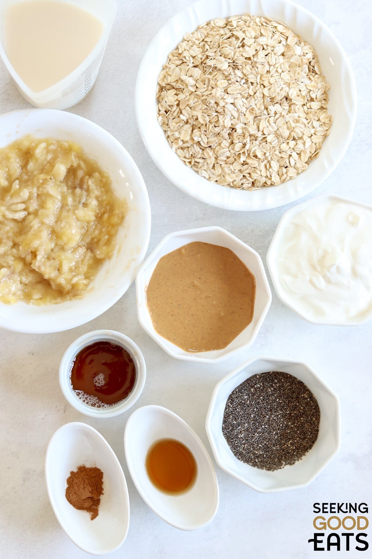 Ingredients needed for making overnight peanut butter banana oatmeal on a white wooden board.