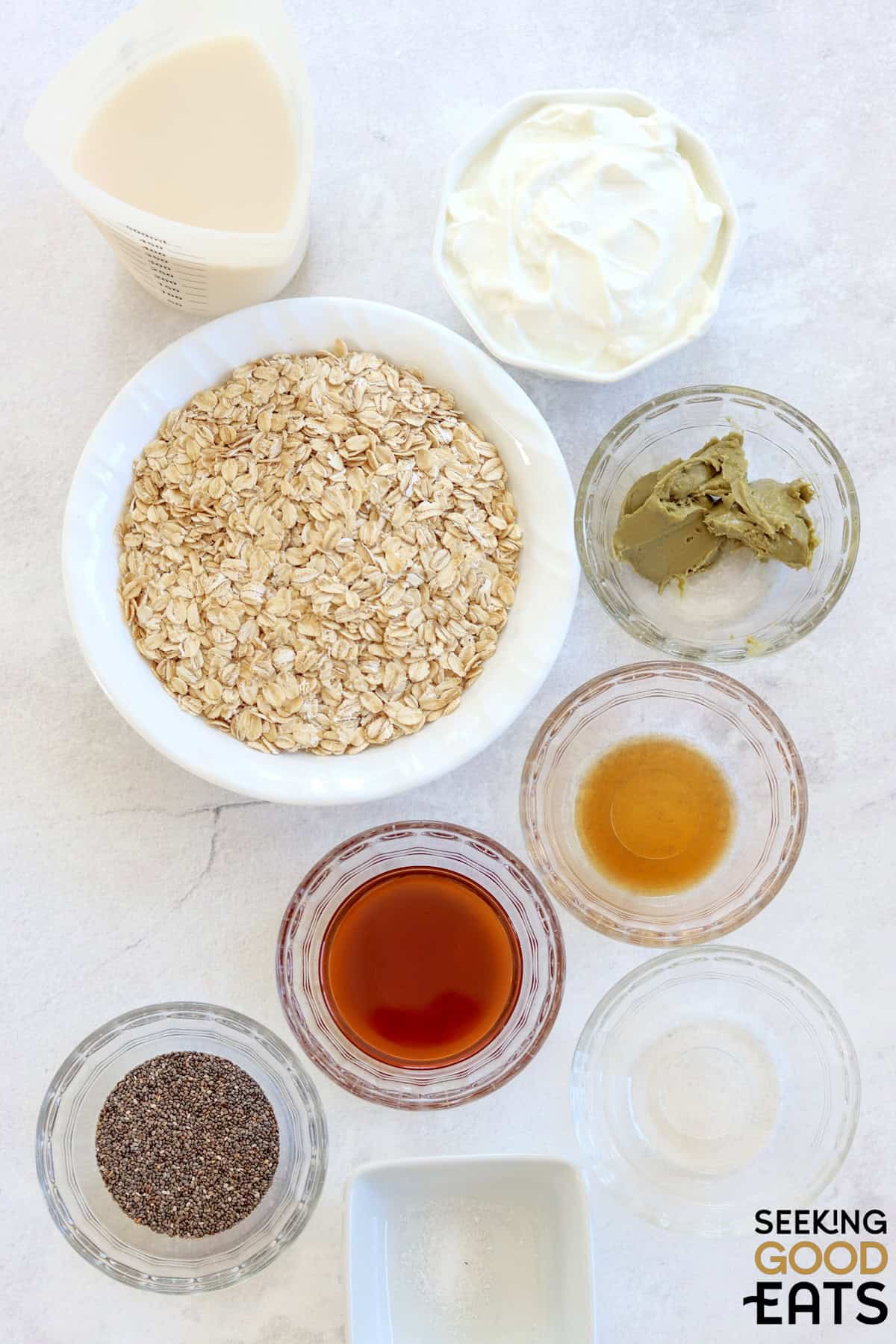 Ingredients needed for making pistachio and cream overnight oats on a white board.