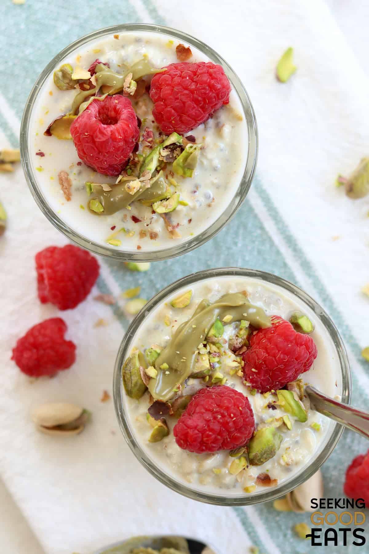Two glass dished of overnight oats with pistachio cream and raspberries.