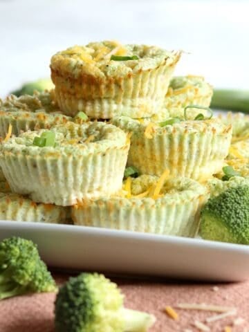 Broccoli cheddar egg bites stacked on a white square plate.