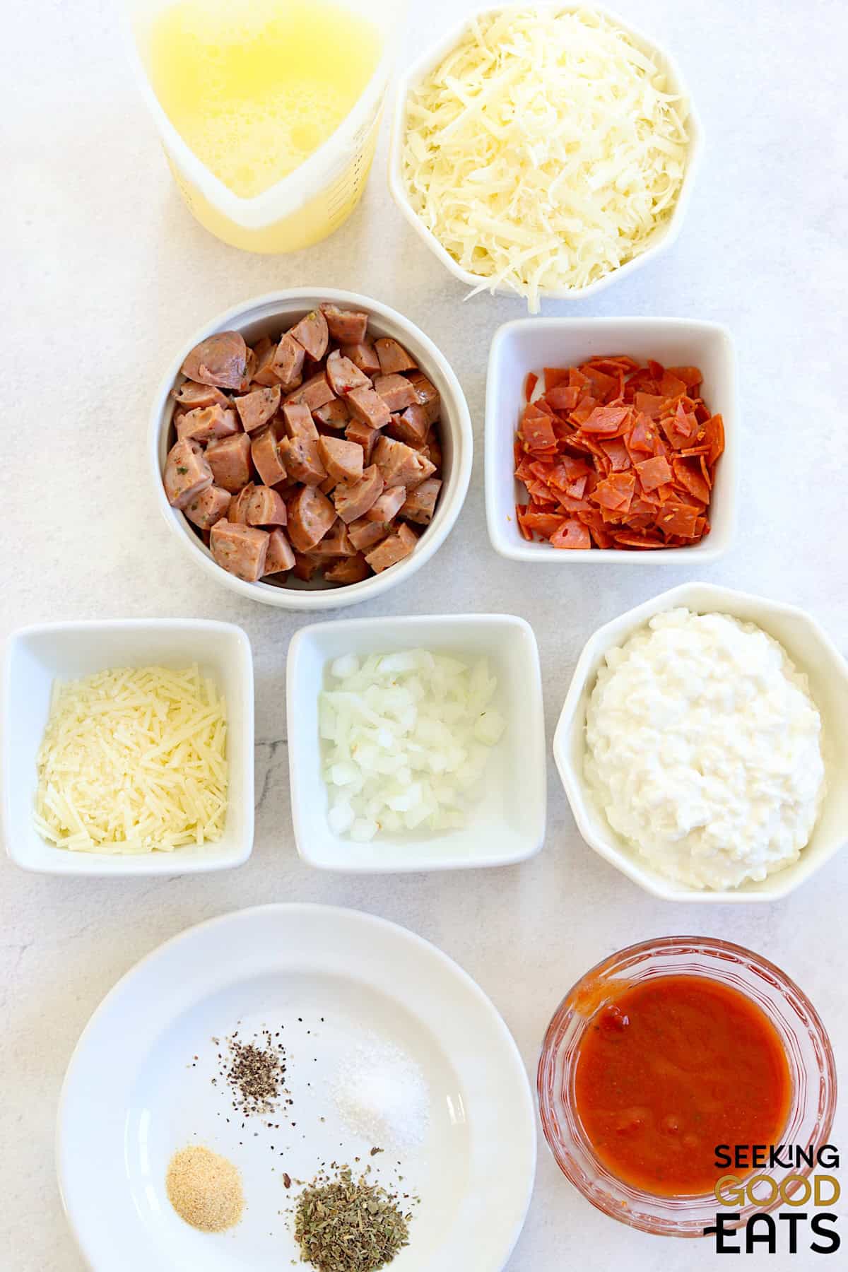 Ingredients needed for making pizza cottage cheese egg bites on a white board.